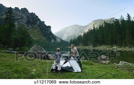 Stock Photo - Father and son pitching tent together. Fotosearch