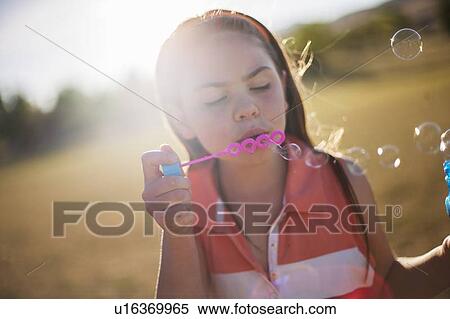 Girl blowing bubbles outdoors View Large Photo Image Stock Photography - Girl blowing bubbles outdoors. Fotosearch