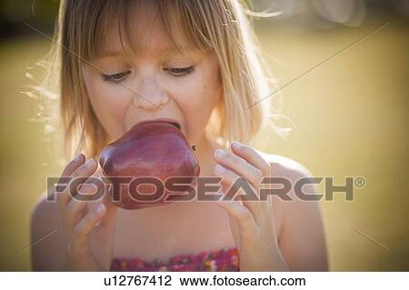 Stock Image - Girl eating apple outdoors. Fotosearch