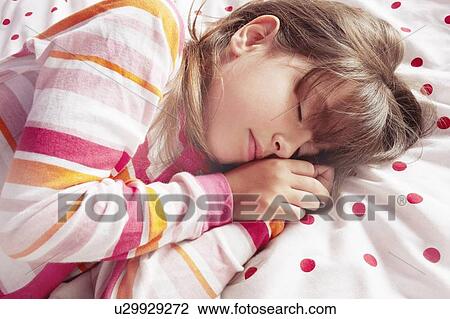 Stock Image - Girl sleeping on polka dot blanket. Fotosearch