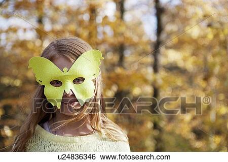 Stock Photograph - Girl wearing butterfly mask in park. Fotosearch