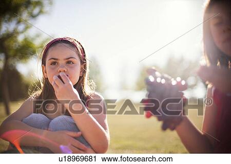 Girls eating fruit in field View Large Photo Image Stock Image - Girls eating fruit in field. Fotosearch