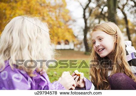 Stock Photo - Girls eating together outdoors. Fotosearch