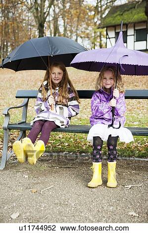 Girls in rain boots and umbrellas in park View Large Photo Image Stock Image - Girls in rain boots and umbrellas in park. Fotosearch