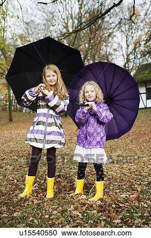 Girls in rain boots and umbrellas in park View Large Photo Image Stock Image - Girls in rain boots and umbrellas in park. Fotosearch