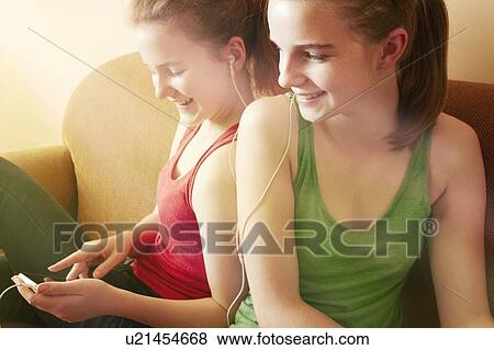Stock Photo - Girls listening to headphones together. Fotosearch