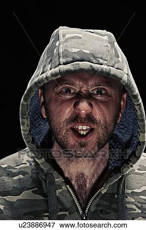 Grimacing man wearing hoodie View Large Photo Image Stock Photo - Grimacing man wearing hoodie. Fotosearch