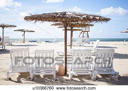 Stock Image - Lawn chairs and umbrella on beach. Fotosearch