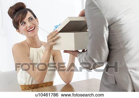 Stock Photograph - Man giving smiling girlfriend present. Fotosearch