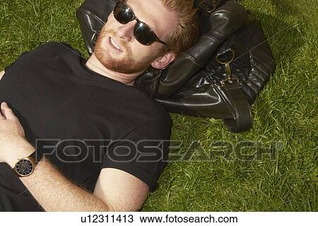 Man laying on bag in grass View Large Photo Image Stock Image - Man laying on bag in grass. Fotosearch