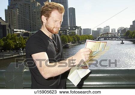 Stock Image - Man reading city map on bridge. Fotosearch