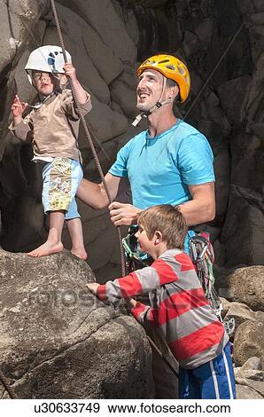 Stock Photo - Man teaching children to rock climb. Fotosearch