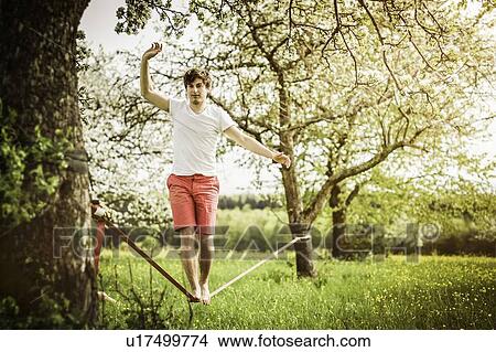 Picture - Man walking on tightrope in field. Fotosearch
