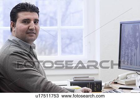 Stock Image - Man working at computer in office. Fotosearch