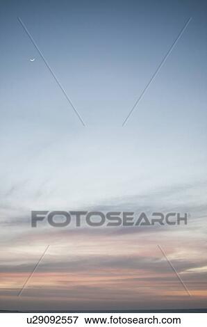 Stock Photo - Moon rising over colorful sky. Fotosearch