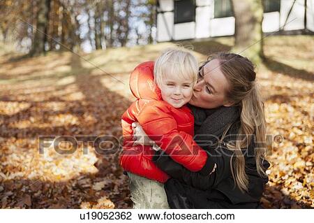 Mother kissing son outdoors View Large Photo Image Stock Image - Mother kissing son outdoors. Fotosearch