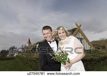 Stock Image - Newlywed couple smiling in field. Fotosearch