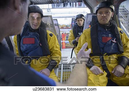 Stock Image - Oil workers in simulated helicopter. Fotosearch