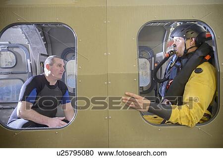 Stock Image - Oil workers in simulated helicopter. Fotosearch