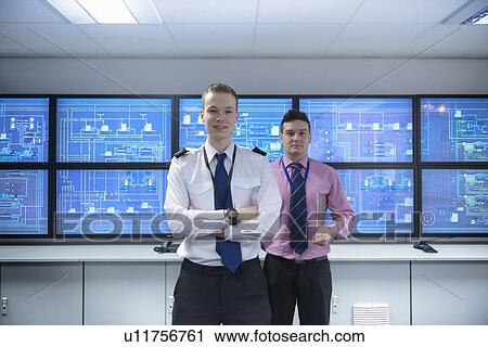 Stock Image - Personnel standing in ships engine room. Fotosearch
