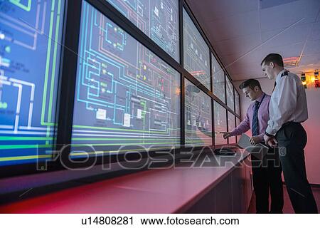 Stock Image - Personnel working in ships engine room. Fotosearch