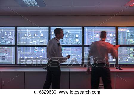 Stock Image - Personnel working in ships engine room. Fotosearch