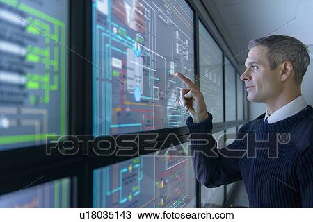 Stock Image - Personnel working in ships engine room. Fotosearch