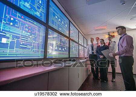 Stock Image - Personnel working in ships engine room. Fotosearch