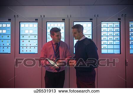 Stock Image - Personnel working in ships engine room. Fotosearch