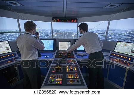 Stock Image - Personnel working on ships bridge. Fotosearch