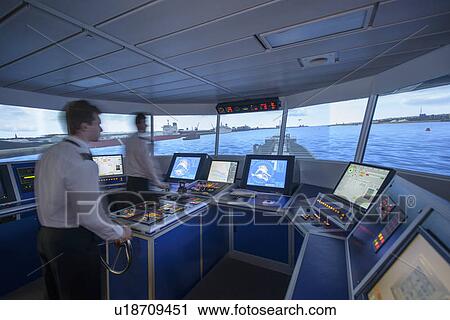 Stock Image - Personnel working on ships bridge. Fotosearch