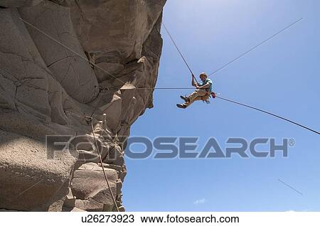 Rock climber abseiling jagged cliff View Large Photo Image Stock Image - Rock climber abseiling jagged cliff. Fotosearch