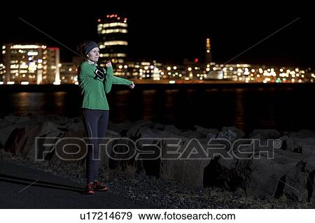 Stock Photo - Runner stretching on waterfront at night. Fotosearch