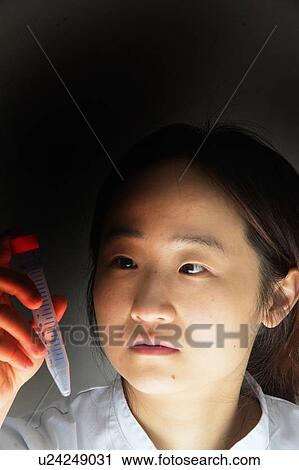 Stock Image - Scientist examining syringe. Fotosearch