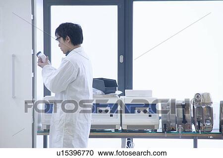 Stock Image - Scientist reading jar label in lab. Fotosearch