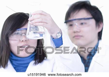 Stock Photograph - Scientists examining liquid in lab. Fotosearch
