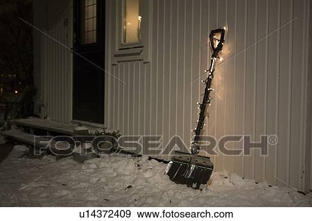 Stock Photo - Shovel with fairy lights in snow. Fotosearch