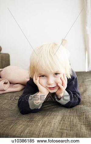 Stock Photography - Smiling boy laying on bed. Fotosearch
