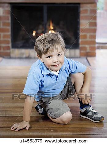 Stock Photo - Smiling boy sitting on wooden floor. Fotosearch