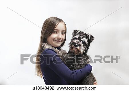 Stock Image - Smiling girl holding dog. Fotosearch