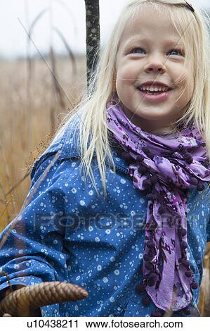 Stock Image - Smiling girl standing in tall grass. Fotosearch