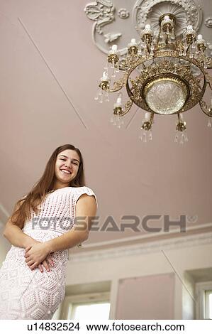 Picture - Smiling girl under ornate chandelier. Fotosearch