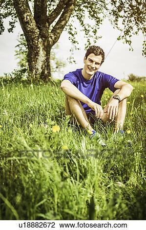 Smiling man sitting in tall grass View Large Photo Image Stock Image - Smiling man sitting in tall grass. Fotosearch