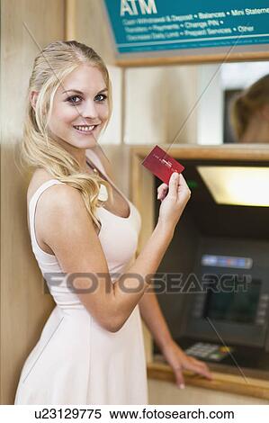 Stock Photography - Smiling woman using ATM. Fotosearch