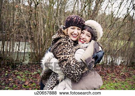 Stock Photo - Smiling women hugging in forest. Fotosearch