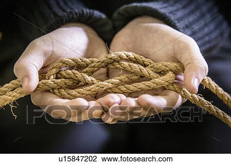 Stock Image - Student tying carrick bend knot in rope. Fotosearch