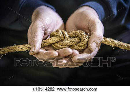 Stock Image - Student tying figure eight in rope. Fotosearch