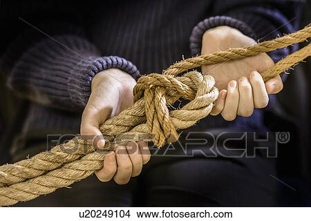 Picture - Student tying sheet bend knot in rope. Fotosearch