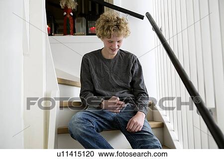 Teenage boy using cell phone on stairs View Large Photo Image Stock Image - Teenage boy using cell phone on stairs. Fotosearch