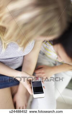 Teenage girls using cell phone together View Large Photo Image Stock Image - Teenage girls using cell phone together. Fotosearch